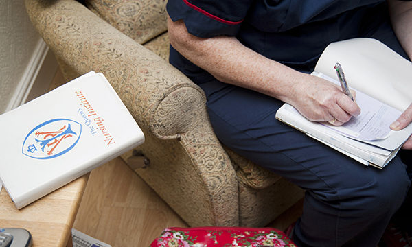 A nurse sitting in an armchair, presumably in someone's home