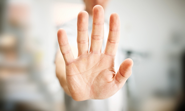 A figure with an open-palmed had raised to protect from aggression 