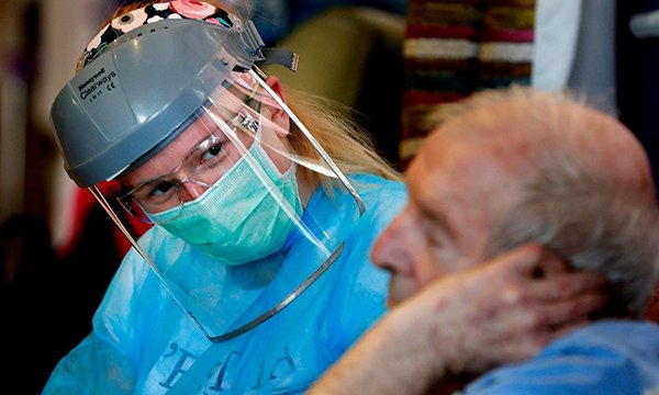 Picture shows a resident of Wren Hall nursing home talking to a medic who is wearing personal protective equipment