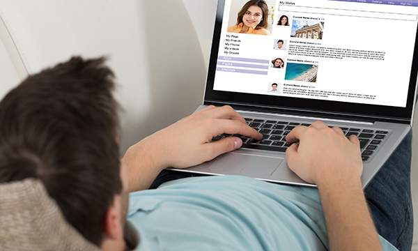 Picture shows a man looking at a dating site on his laptop.